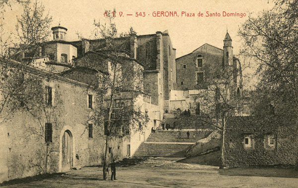 Vista parcial de la plaça de Sant Domènec amb l'edifici de les Àligues en primer terme a l'esquerra. Al fons, el convent de Sant Domènec utilitzat com a caserna militar. 1900