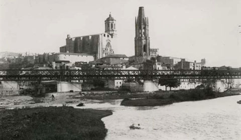 Punt de confluència entre els rius Ter i Onyar. A la part central, el pont del Ferrocarril. Al fons, la Catedral de Girona i el campanar de l'església de Sant Feliu. A la dreta, la passarel·la del Portal de la Barca. 1880-1905