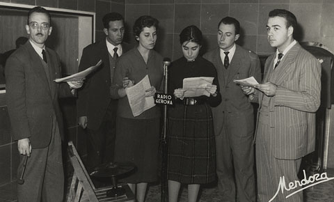 Retransmissió d'un programa de ràdio als estudis de Radio España de Gerona EAJ, a Girona. S'identifiquen, el primer a l'esquerra, a Josep Capella Riera, i el segon des de la dreta, Narcs-Jordi Aragó. 1965