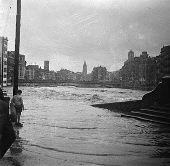 Inundacions provocades pel desbordament dels rius Ter i Onyar. El riu Onyar desbordat a l'altura de la rambla Pi i Margall. En primer terme, les escales del pont del Pes de la Palla, en segon terme, el pont de Pedra. 29 d'octubre 1920