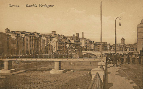 La rambla de Jacint Verdaguer a l'altura del pont del Pes de la Palla. En segon terme, el pont de Pedra i al fons, el campanar de l'església de les Bernardes. 1913-1920
