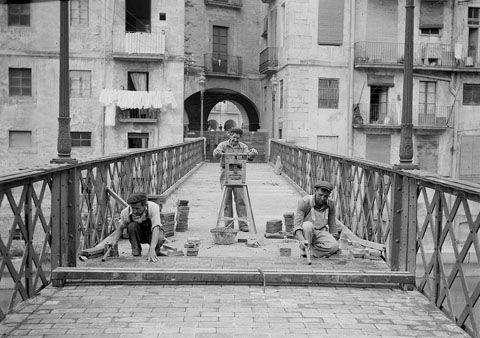 Obres per a la substitució del paviment del pont de Sant Agustí. S'observen tres obrers realitzant les tasques de pavimentació enrajolada del pont, de la constructora Torras. 1922