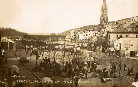 La plaça Independència en un dia de mercat. Al fons a l'esquerra, la barraca de fusta del cinema Paral·lel i que posteriorment es convertiria en el cinema Coliseo Imperial i es traslladaria a un edifici fix al solar del costat, ocupat pels carros. 1903-1906