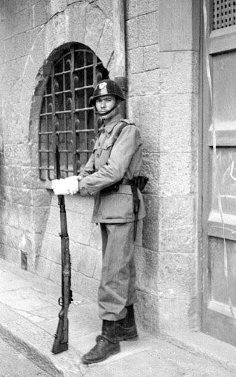 Diada de Corpus. Retrat d'un soldat davant la casa de la família Ribot al carrer Albereda. 1949