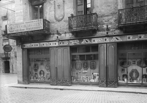 Façana i aparador de la galeria Foto Lux en la cantonada amb el carrers Ciutadans. Sobre la galeria hi ha el local de la Secció Femenina de la Falange. 1950