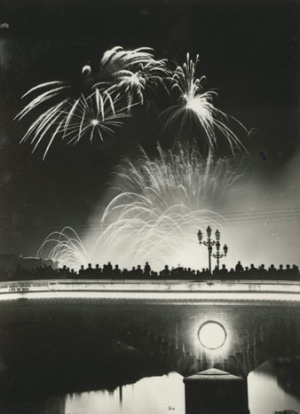 Espectadors al pont de Pedra observant el tradicional castell de focs artificials que clausura les Fires de Sant Narcís. 1960