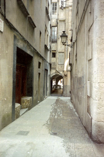 El carrer de les Olles a l'encreuament amb Mercaders. Al fons, el carrer de les Ferreries Velles i la volta d'accés a la Rambla de la Llibertat. L'edifici de la dreta va ser enderrocat per obrir-hi una plaça. 1986