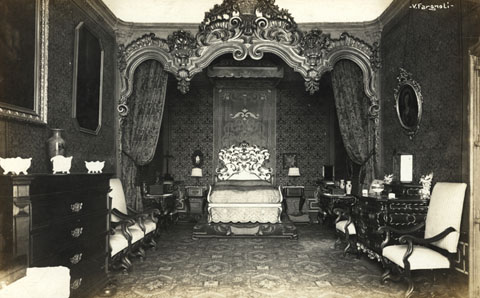 Dormitori reial de la casa Carles. Del mobiliari i la decoració, en destaquen el llit amb capçalera, les calaixeres, les cadires, les peces de ceràmica i els quadres. En aquest dormitori hi van dormir D. Juan Bosco i hi va reposar Alfons XIII. 1910-1915