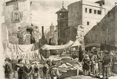 Mercat a la rambla de la Llibertat, on es fa la venda de queviures, teixits i altres productes. El mur que s'observa correspon al baluard de l'Areny, enderrocat el 1869. 1870-1872